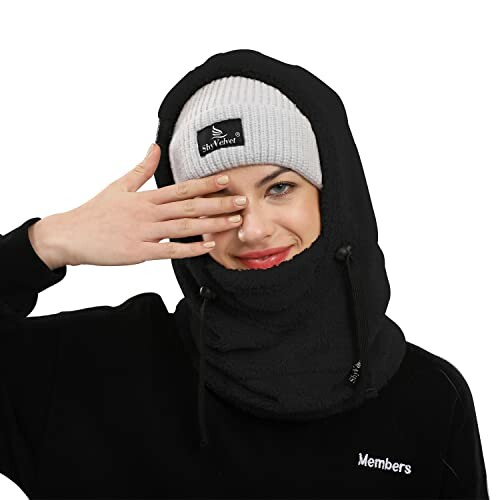 Woman wearing a gray beanie and black hooded scarf